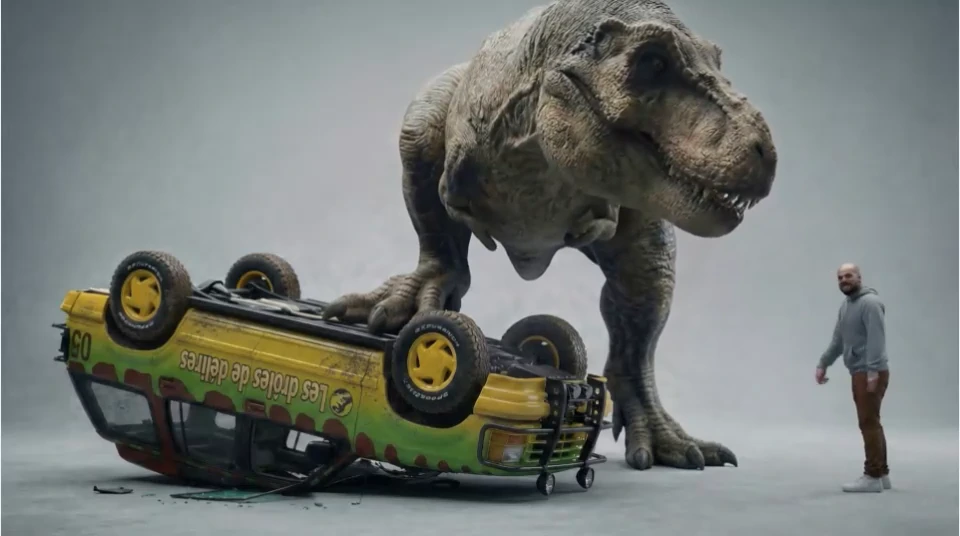 The T-Rex plays with an overturned car while the presenter remains perfectly calm.